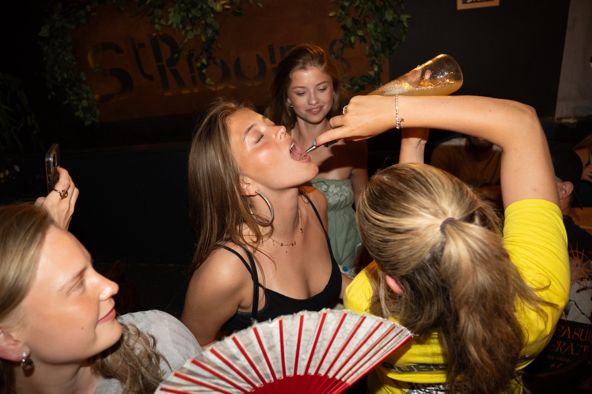 Young partygoers sharing a wild moment during a bar crawl in Nice as a guide pours a drink during a fun challenge capturing spontaneous energy laughter and the high intensity party atmosphere of an unforgettable nightlife experience on the French Riviera